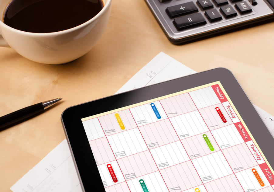 Workplace with tablet pc showing calendar and a cup of coffee on a wooden work table close-up-3